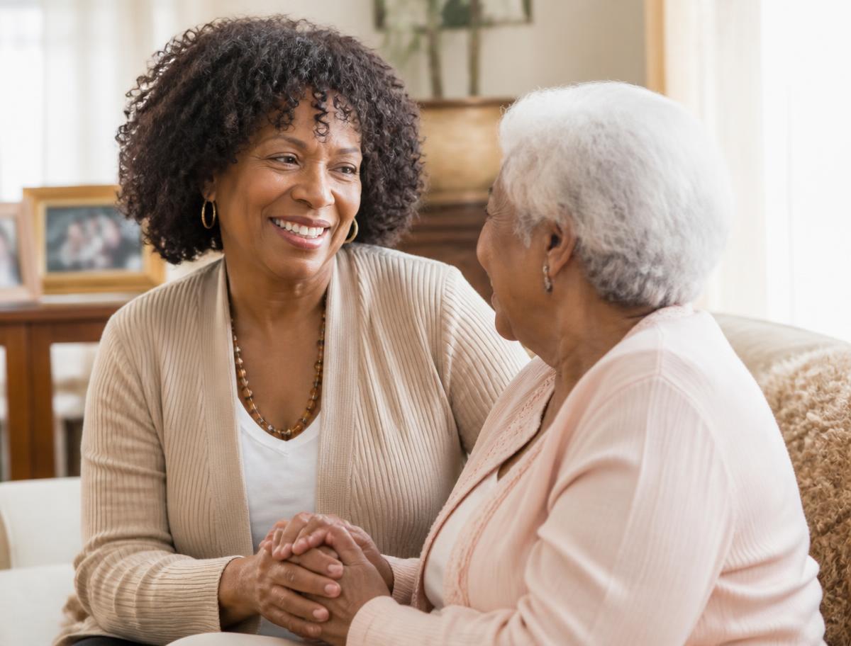 Brenda sitting with a senior client, holding hands and smiling